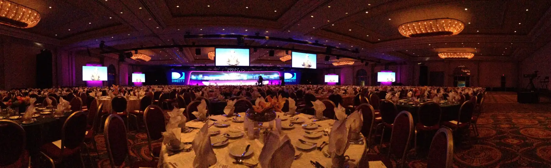 Large scale corporate gala dinner in a grand ballroom with LED video walls and branded stage setup by corporate event management in Los Angeles
