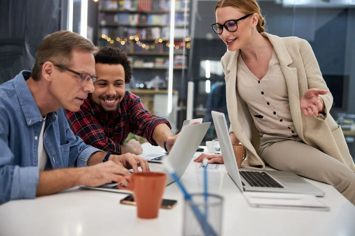Three colleagues collaborating on laptops during a team building company event idea for employees