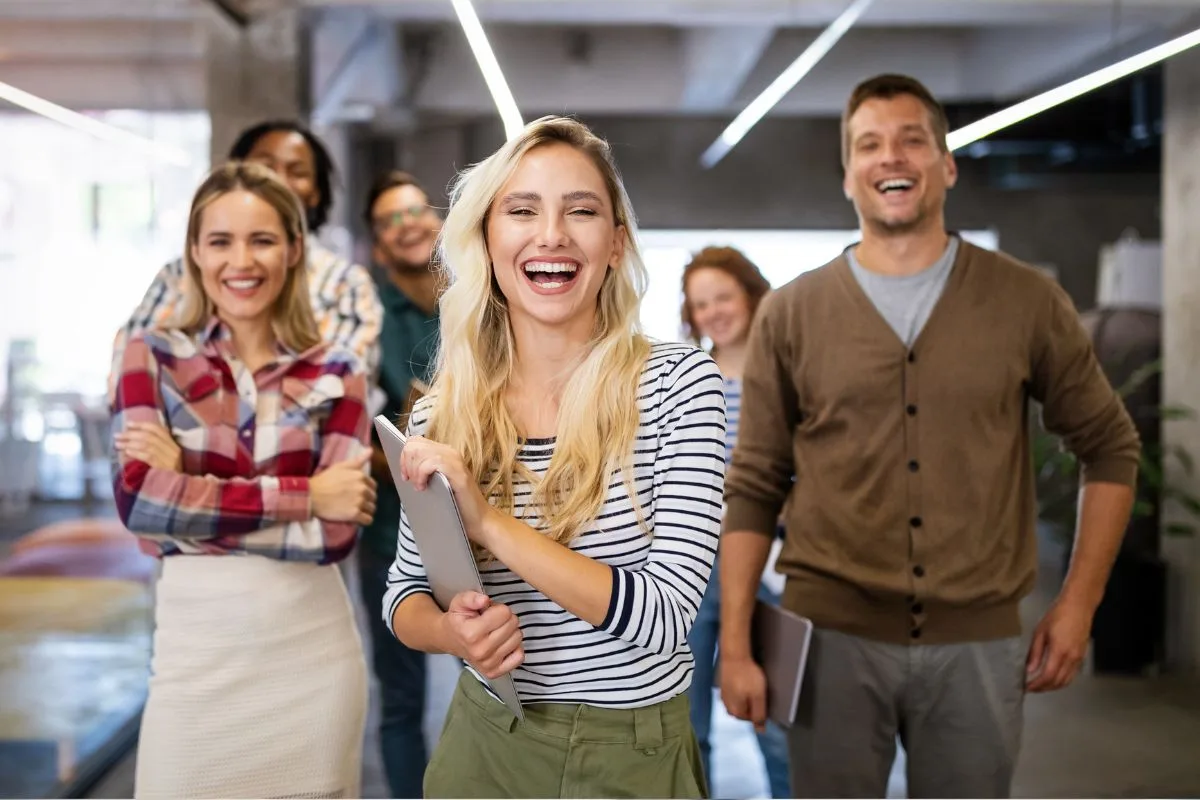 Happy team of employees laughing and walking through the office after a fun company event idea for employees
